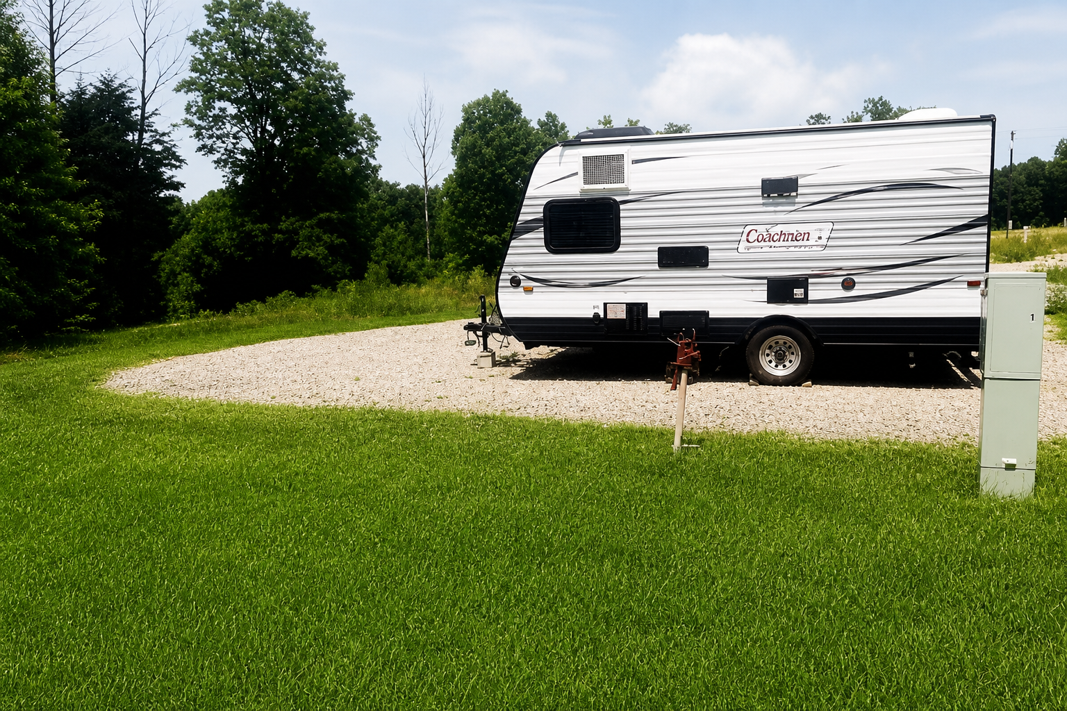 Travel trailer parked on concrete pad with utility pedestal at Kumberland Campground